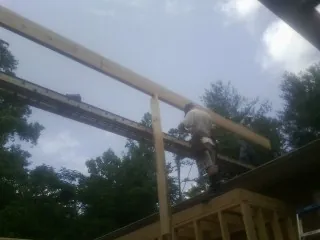 Carpenter setting a ridge beam over a new addition frame — Ice Dam Removal by Roofing Brothers in Wendell