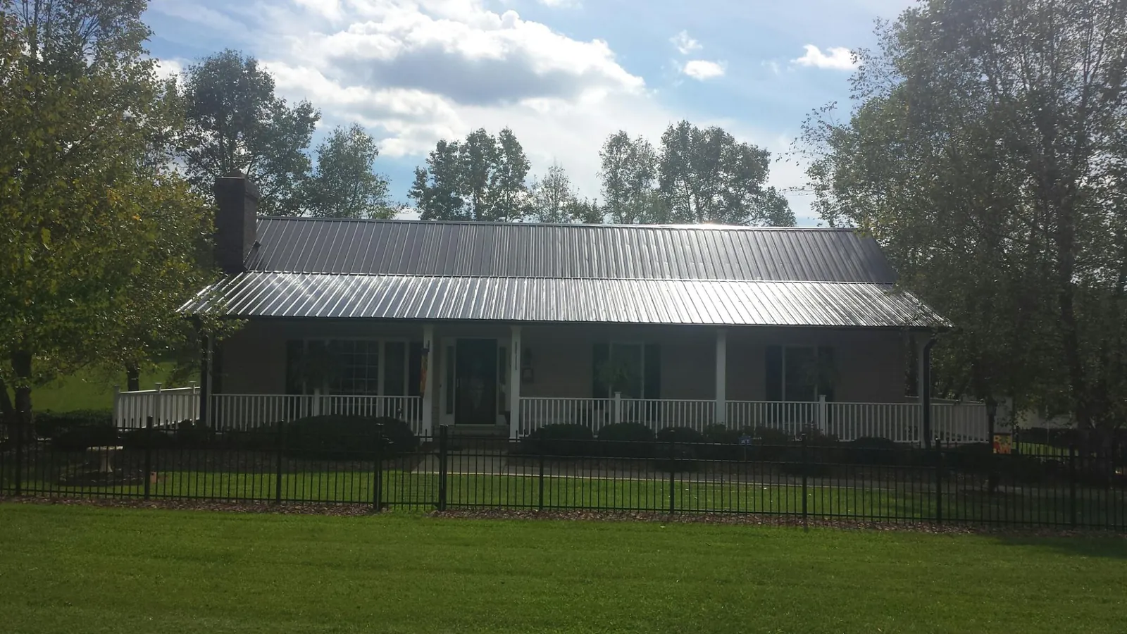 Gray metal roof on a brick ranch with a full width front porch — Gutter Guard Installation work by our crew in Wendell